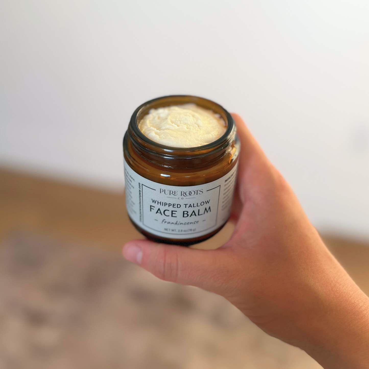 Jar of whipped tallow balm with a label on a light background