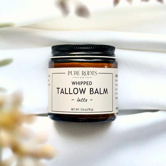 Jar of whipped tallow balm labeled 'Pure Roots' on a white background with plants.