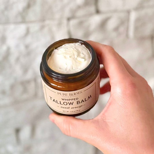 Hand holding a jar of whipped tallow balm with a blurred background
